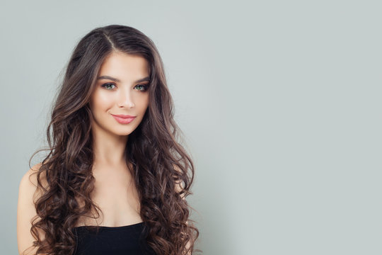 Smiling mode brunette woman with natural makeup and long wavy hair on gray banner background
