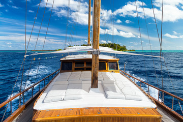 luxury sailing boat yacht in front of tropical paradise maldives island resort with coral reef and...