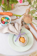 Close up of painted egg wrapped in a linen napkin shaped like bunny ears on Easter breakfast table. Polish Easter