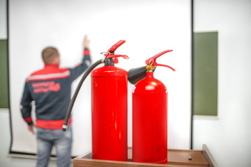 Uniformed fireman gives a lecture or instruction on fire safety. The instructor teaches the use of fire extinguisher