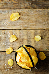 Potato chips with salt on a wood background