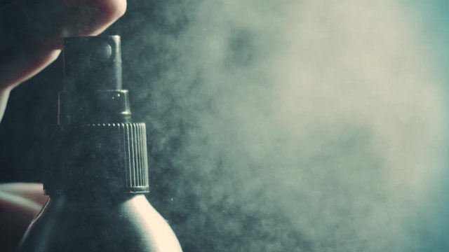 Spraying water or perfume against dark background, super slow motion. Shot on Red