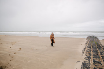 Happy woman walkin on the beach along the North Sea. Outside is cold and rainy