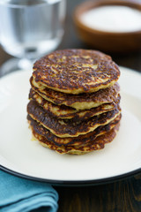 Potato pancakes draniki served on a white plate. Dark wooden table, blue linen napkin, high resolution