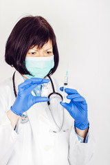 Doctor in white lab coat  holding medical ampoule and syringe