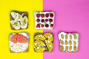 Healthy breakfast toasts with peanut butter, banana, chocolate, chia seeds, raspberries, almond, yogurt, oranges, grapefruit. Color background