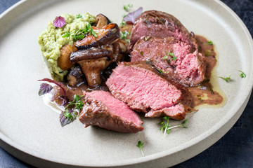 Barbecue aged sliced venison sirloin with mushroom in gammon red wine sauce and mashed potatoes with ramson as top view a modern design plate © HLPhoto
