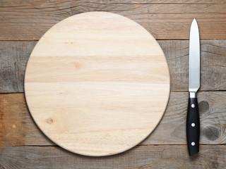 Chopping board and knife on old wooden table top view