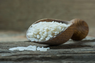 turkish raw white rice grains with burlap sack in wooden shovel on black wooden background, healthy food uncooked legumes concept 