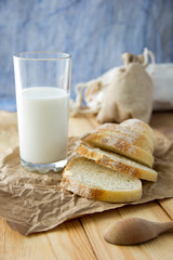 a glass of milk and breaded bread on a wooden table and scattered crumbs on a booty background