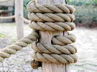 Thick rope on a wooden column forming a knot as part of the rope fence.