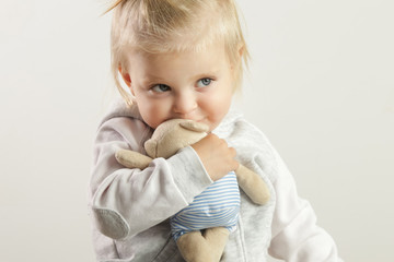 An adorable baby girl hugging with her favorite soft toy - obrazy, fototapety, plakaty