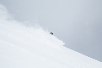 Skier disappearing in soft snow in backcountry ski turn through deep snow in Hokkaido, Japan.