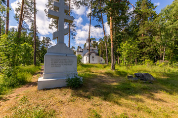 Fototapeta na wymiar Cross and white church in the forest. Island Valaam