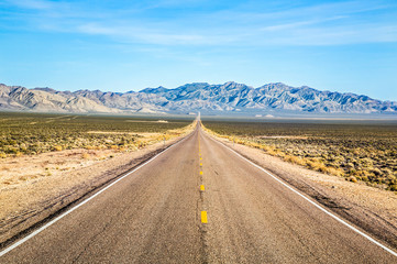 Wide open road and distant mountains in wide open Nevada desert along the Extraterrestrial Highway.