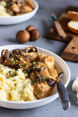 Chicken breast in cream sauce with mushroom, onion and thyme served with couscous in a white plate.