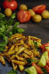 Freshly cooked fried potatoes with onions and mushrooms close-up on a plate. ebony table. vertical view of the dish.
