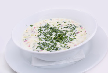 Okroshka. Summer light cold yogurt soup with cucumber, radish, eggs and dill on white plate. Close-up. Top view