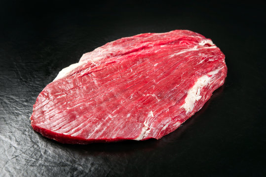 Raw dry aged wagyu flank steak as closeup on black background with copy space