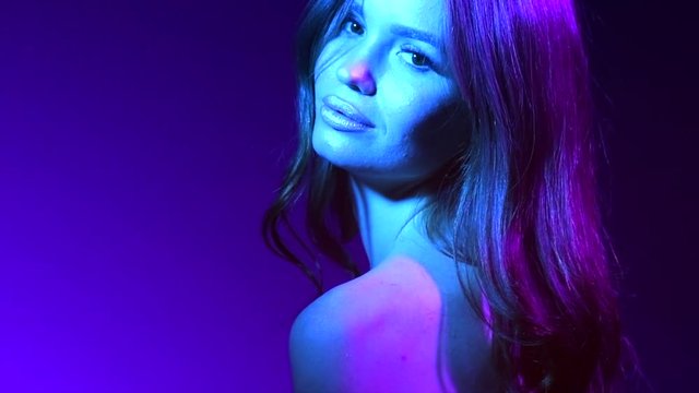 Colorful portrait of beauty sexy model girl. Beautiful seductive woman posing. Gorgeous Brunette girl in neon light. Beauty Glamour sensual lady with long curly hair posing in vivid lights 4K Slowmo
