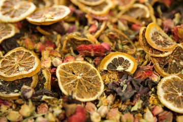Mix of fruit and herbal tea. Slices of lemons and oranges and pomegranate flowers. Close up. 
