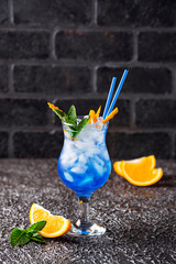 Blue cocktail drink with ice and orange