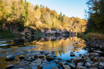 beautiful golden sunrise over forest river with sandstone cliffs on the shores
