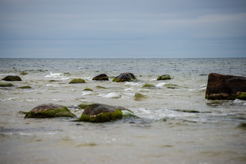 Fototapeta na wymiar stormy sea beach with large rocks in the wet sand