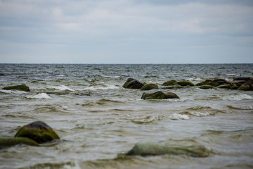 Fototapeta premium stormy sea beach with large rocks in the wet sand