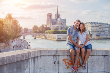 Happy couple hugging near Notre-Dame cathedral in Paris. Tourists enjoying their vacation in...