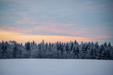 colorful sunset light over fields of snow in winter
