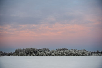Fototapeta na wymiar colorful sunset light over fields of snow in winter