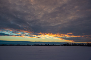 colorful sunset light over fields of snow in winter