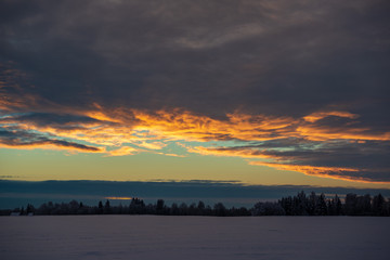 colorful sunset light over fields of snow in winter