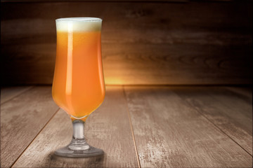 Delicious colorful unfiltered hazy IPA pale ale craft beer in tulip glass on wood table, with copy space