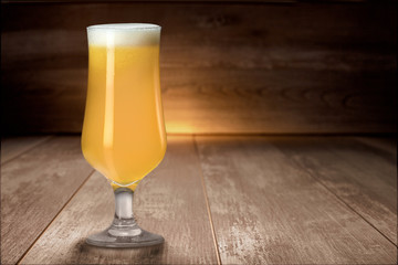Hazy NEIPA New England IPA pale ale craft beer, on wood surface, rich frothy foam head with copy...
