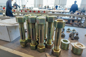 Large bolts with screwed nuts in metalworking factory