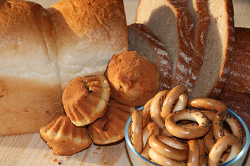 Loaf and slices of fresh bread on a sunny table, muffins and donuts .. Healthy food and healthy ecological product.