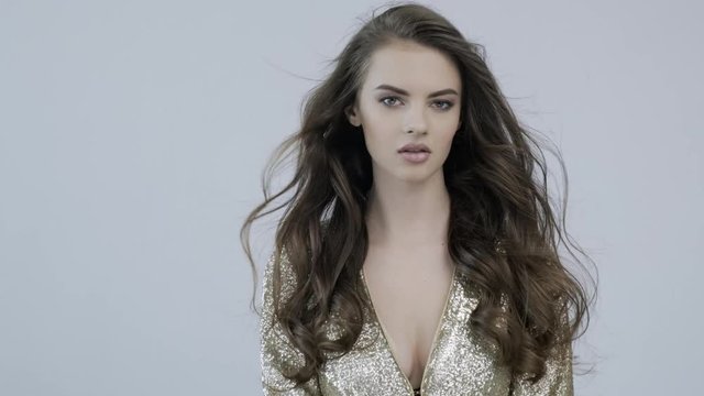4k footage of a beautiful young woman with curly long  brown hair. Fashion model looks to the camera. Stunning face of a caucasian girl. Sexy model with a beautiful eyes. Slow motion. Beauty concept