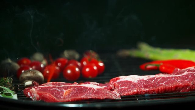 Super slow motion of falling raw beef steaks on grill. Filmed on high speed cinema camera, 1000 fps.