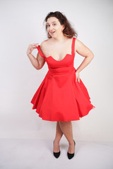 plump woman in a red pinup dress. chubby fashionable girl standing on white background in Studio