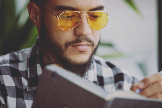 Young man thinking and writing his creative idea or planning future days into notebook closeup