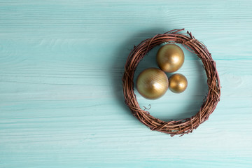 Obraz na płótnie Canvas golden eggs in the nest over wooden background with copy text