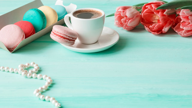Coffee, pink and white tulips and macarons on the white wooden table. Breakfast. Coffee break.