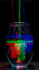 Multi-colored water pouring into a vase