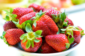 Beautiful red strawberry. Heap of fresh strawberries in ceramic bowl on a rustic white background on the table. 