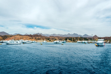 seascape, blue sea with mountains in the background and several yachts in the distance