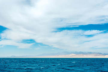 Fototapeta na wymiar Seascape, view of the blue sea with high bald mountains in the background