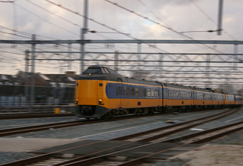 Obraz premium yellow train or intercity driving very quick with motion blur, scenic wallpaper