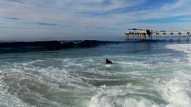 Aerial view of surfers enjoying waves in La Jolla with the scripps pier institute of oceanography on the background, La Jolla, San Diego, California, USA